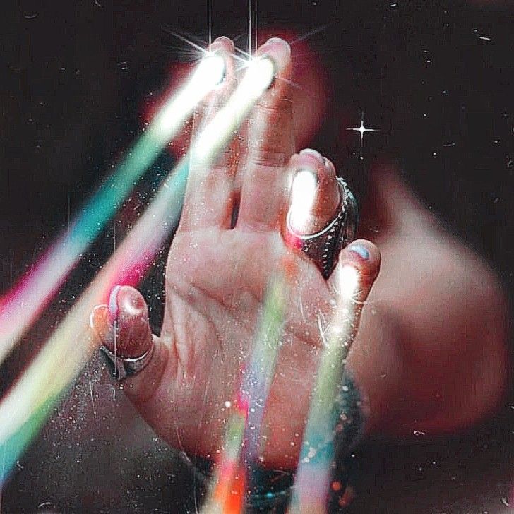 a person holding their hand up in the air with colored beams coming out of it