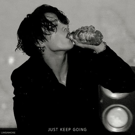 a woman drinking from a bottle while sitting in front of a speaker with the words just keep going written on it