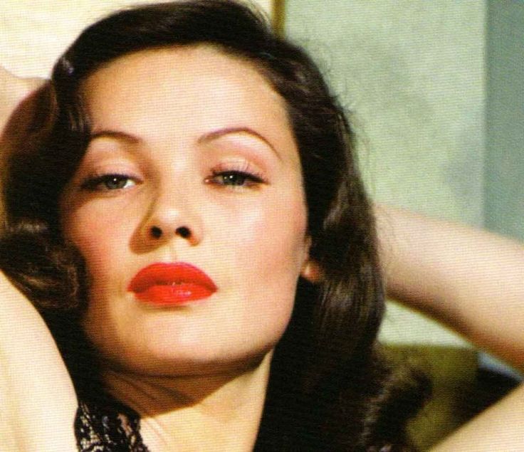 a woman with dark hair and red lipstick posing for a photo in front of a mirror