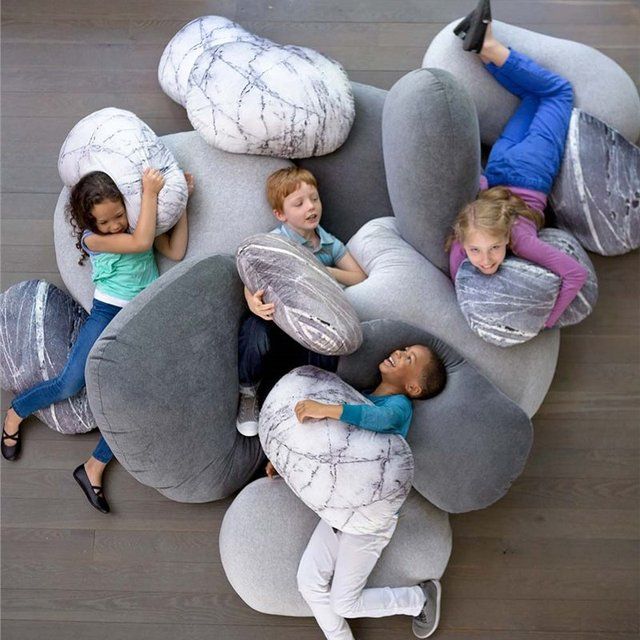 four children laying on bean bag chairs with their arms around each other and looking up at the sky