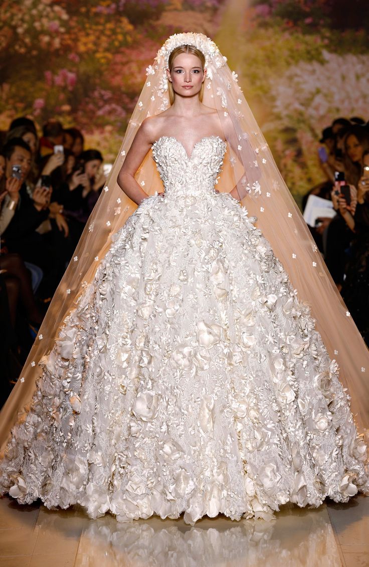 a woman in a white wedding dress on a runway