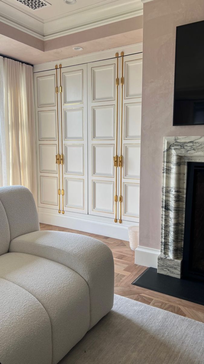 a white couch sitting in front of a fire place next to a tv mounted on a wall