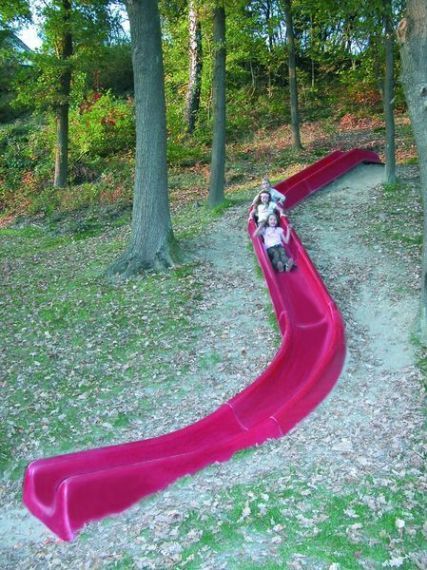 an image of a pink slide going down the side of a hill with trees in the background