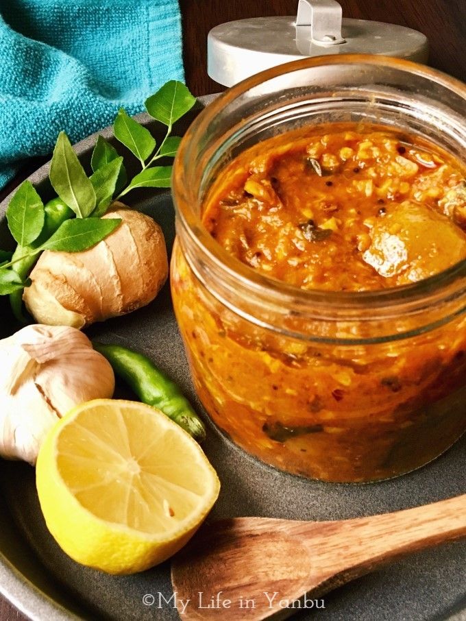 a glass jar filled with food sitting on top of a plate next to lemons and garlic