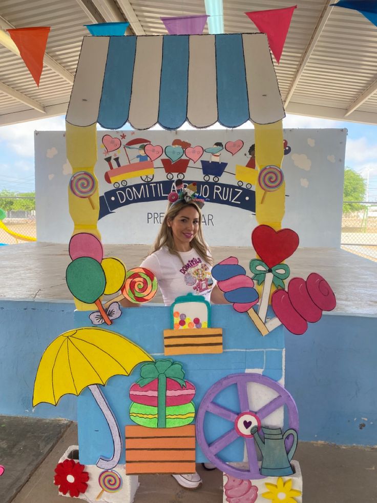 a woman standing in front of a colorful cart with balloons and decorations on it's sides