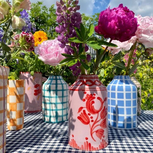 four vases with flowers in them sitting on a checkered cloth tablecloth outdoors