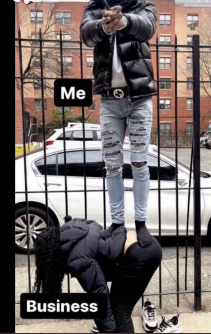 a man standing on top of a metal fence next to a woman in ripped jeans