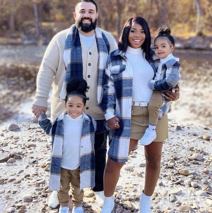 a man, woman and two children are standing in front of a river with rocks