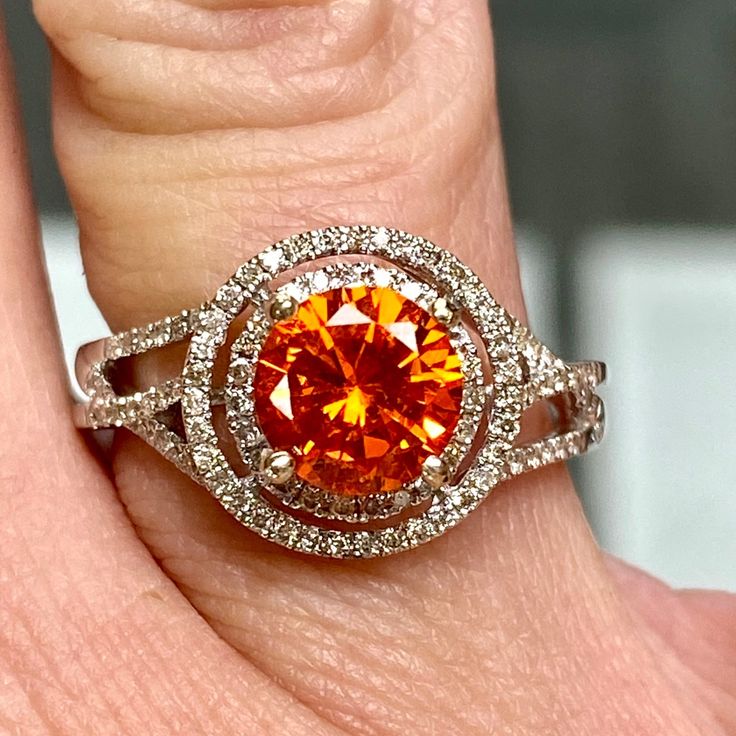 a woman's engagement ring with an orange and white diamond