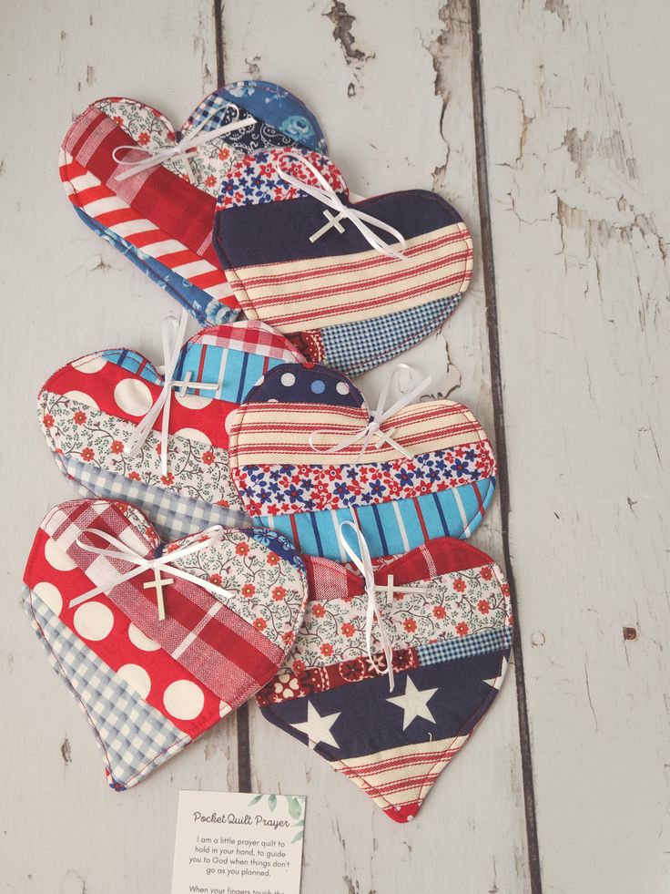 several patriotic heart shaped ornaments on a white wooden surface with a note attached to them