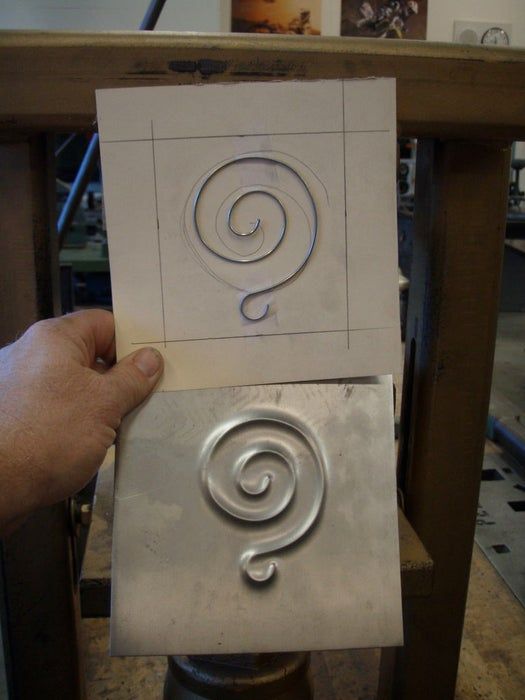 a person holding up a piece of paper with a spiral design on it