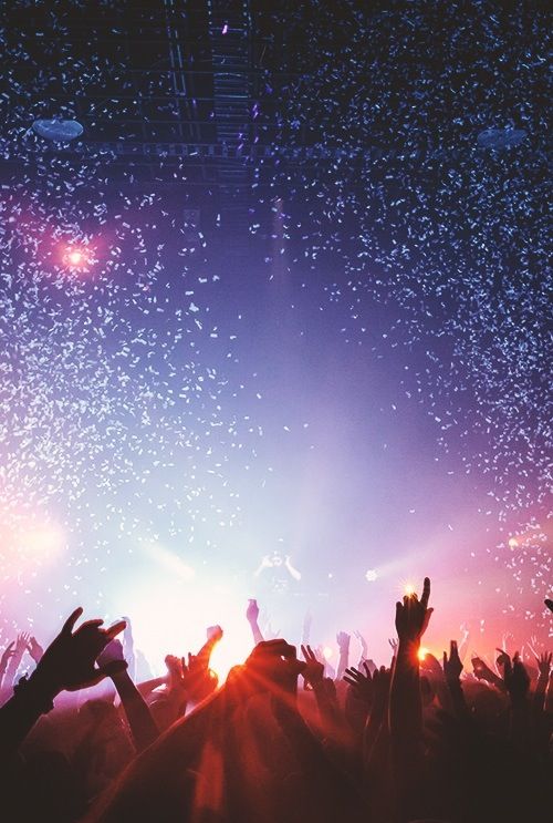 silhouettes of people at a concert with confetti in the air