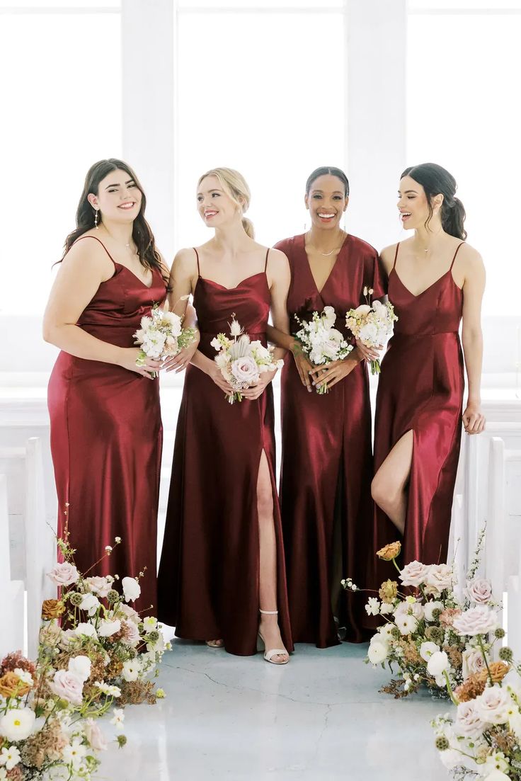 the bridesmaids are all dressed in maroon dresses and holding bouquets with white flowers