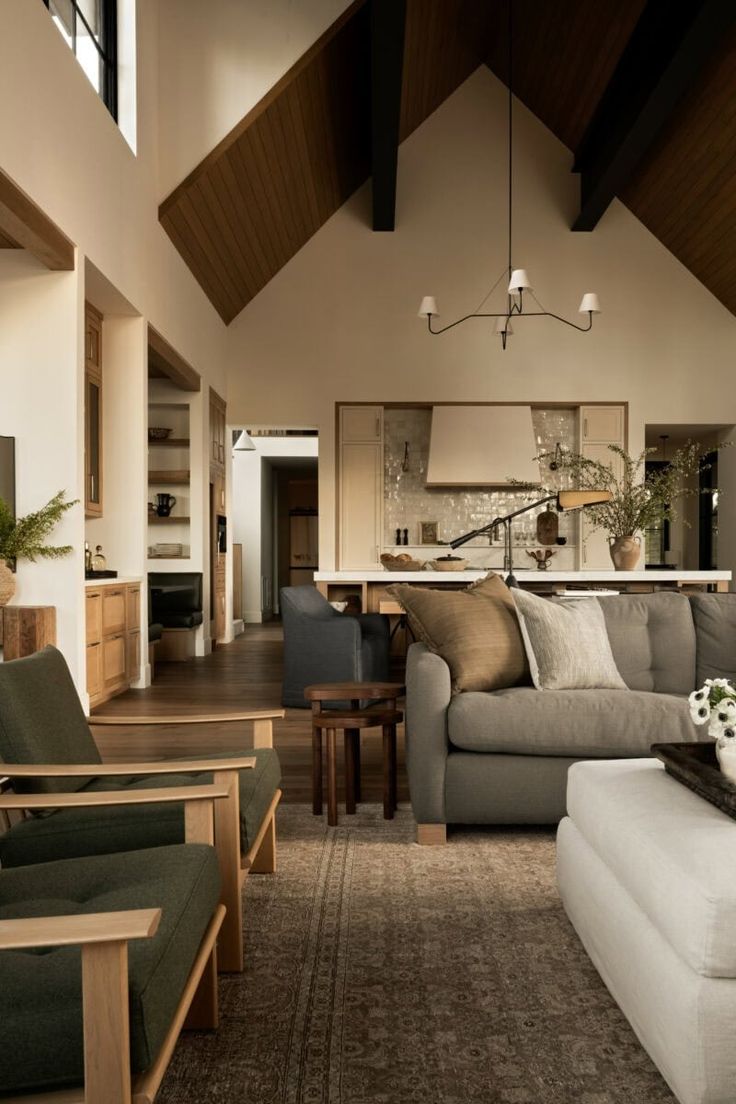 a living room filled with furniture and a large window covered in wooden beams on the ceiling