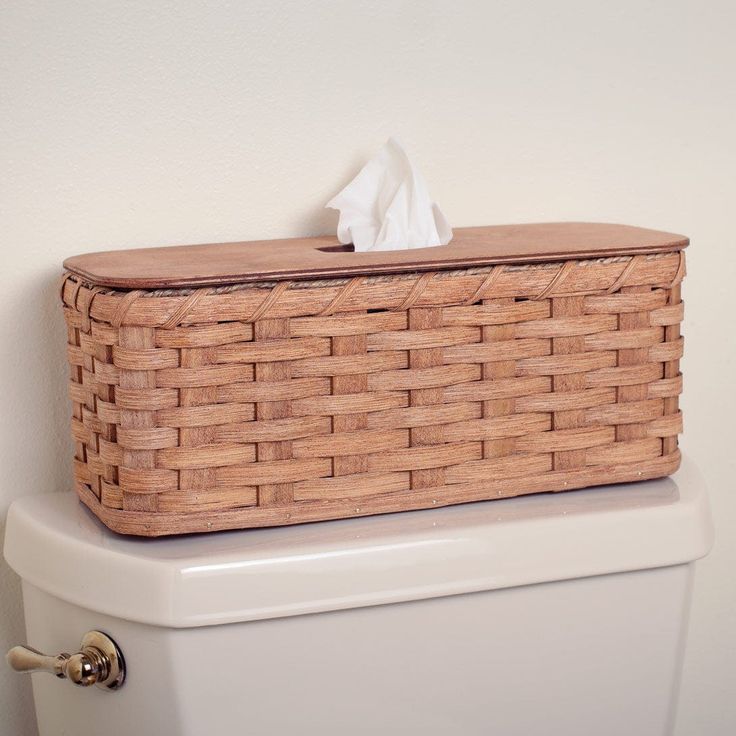 a basket sitting on top of a toilet next to a roll of white tissue paper