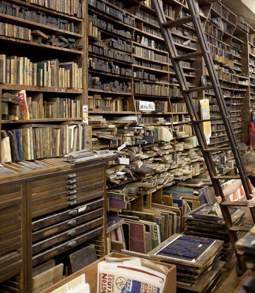 a room filled with lots of books next to a ladder