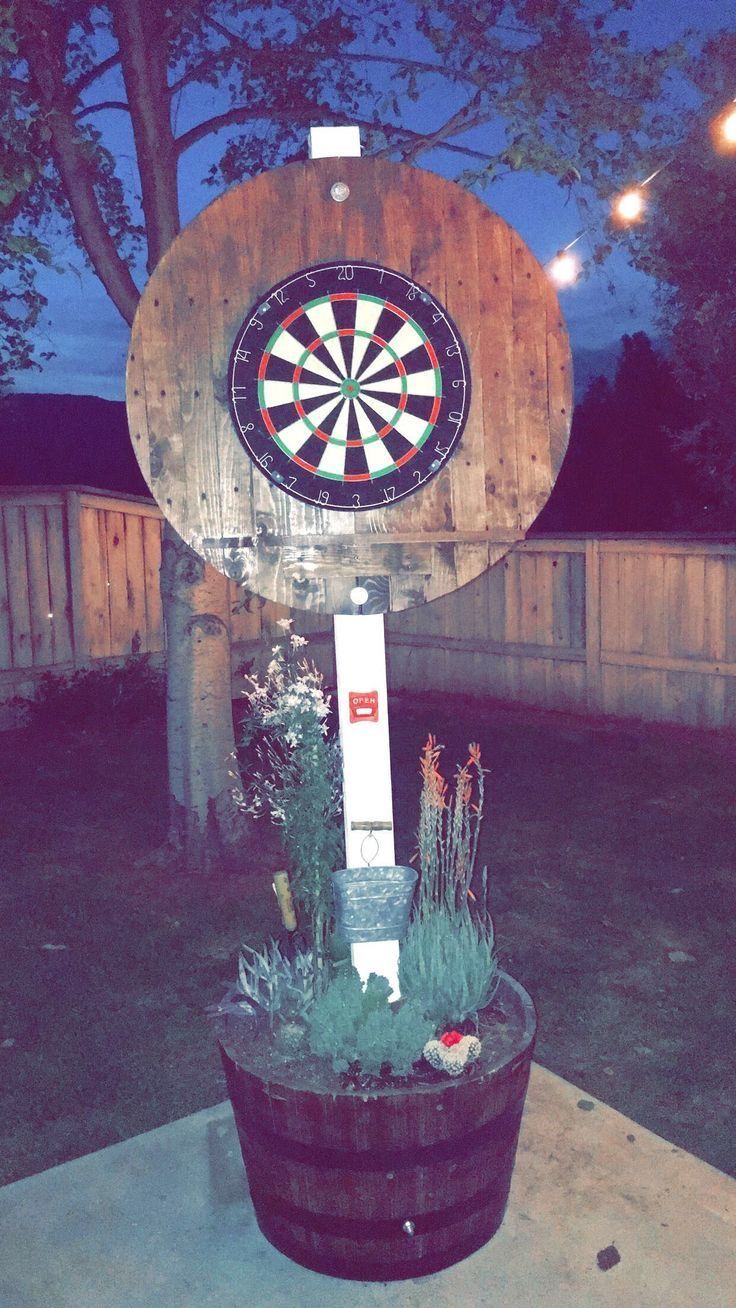 a dart board mounted to the side of a wooden sign on top of a barrel