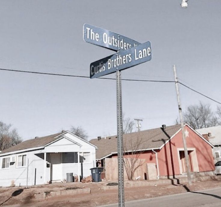 a street sign on the corner of two streets in front of some houses and trees