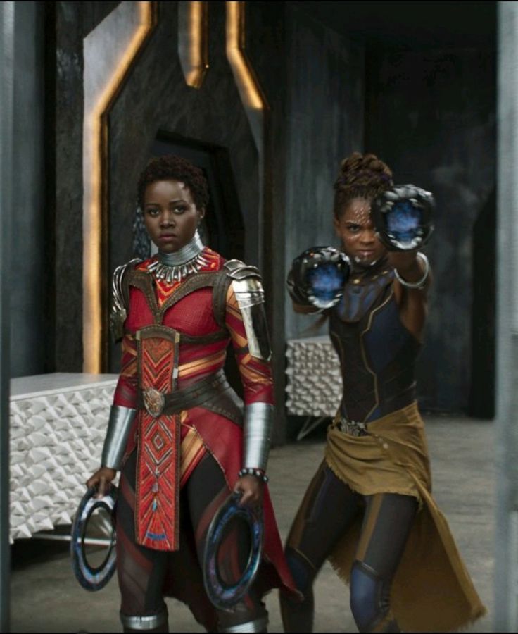 two women dressed in futuristic garb walking into a building