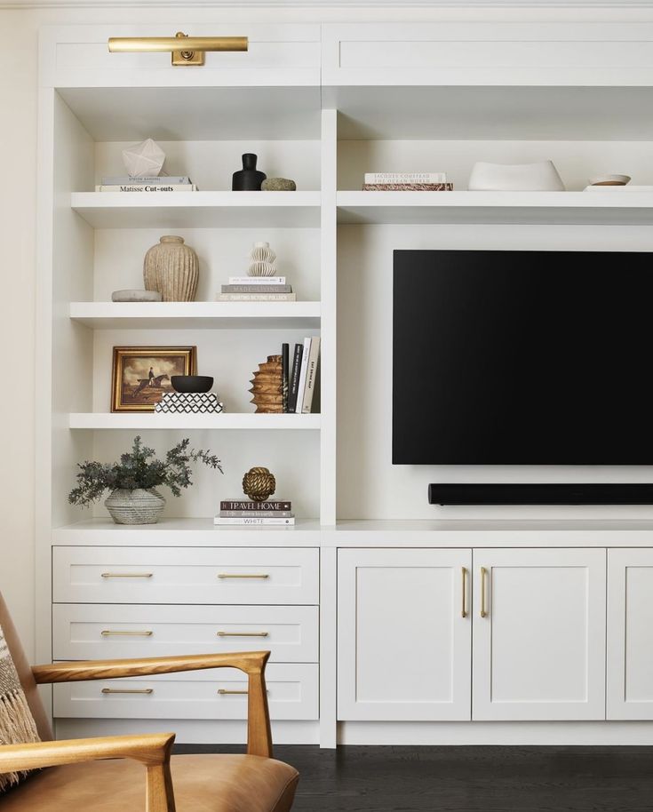 a living room filled with furniture and a flat screen tv mounted on a white wall