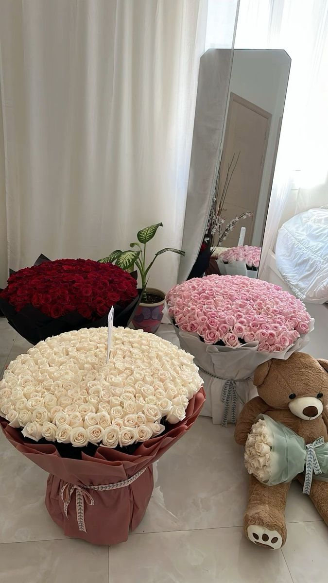 two teddy bears sitting on the floor in front of flowers and a large round cake