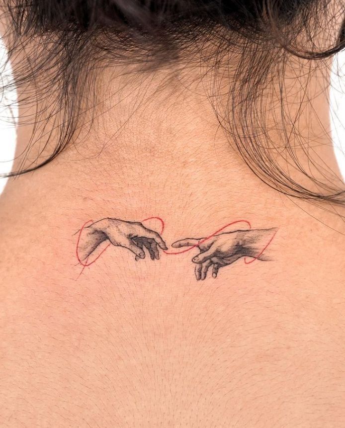 the back of a woman's neck with two hands touching each other over it