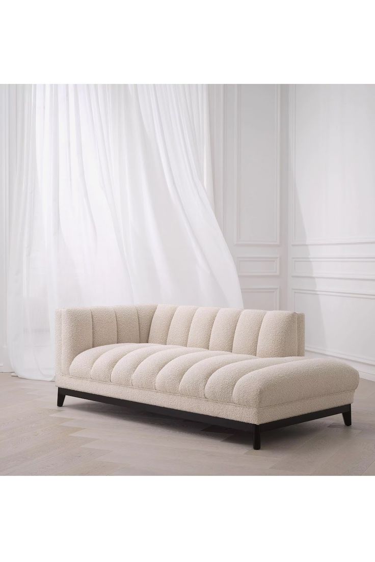 a white couch sitting on top of a hard wood floor next to a curtained window