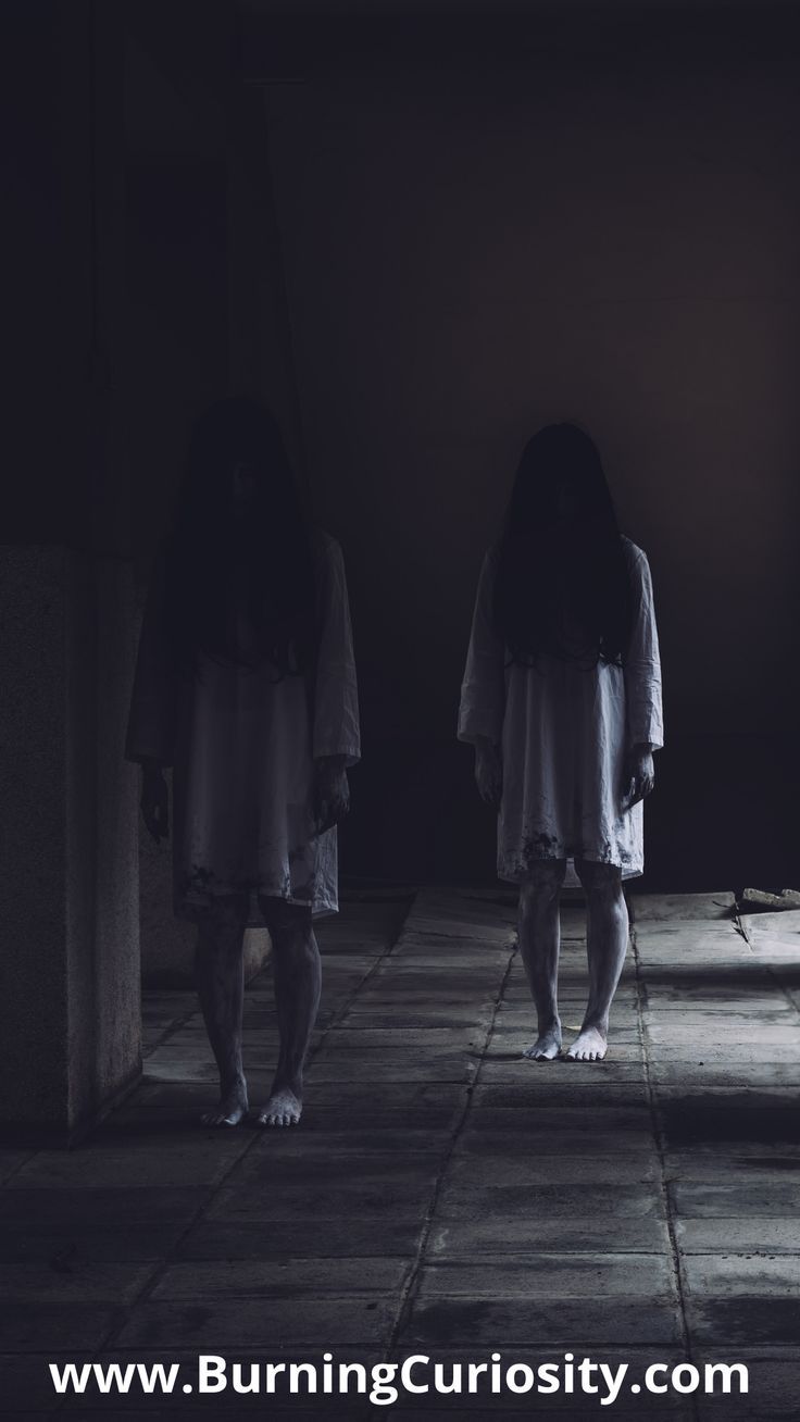 two people standing in the dark with their backs turned