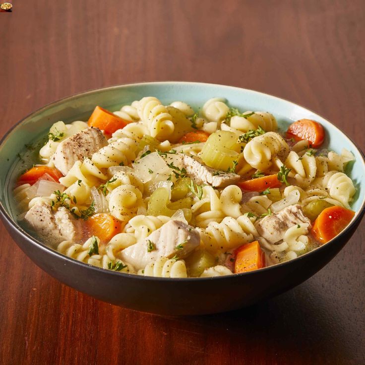 a bowl filled with pasta and vegetables on top of a wooden table