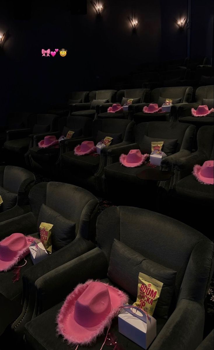 an empty movie theater with pink hats on the seats and popcorn bags in front of them