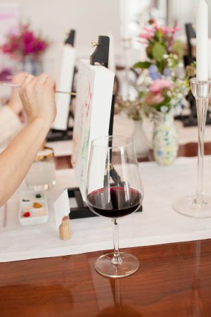 two people sitting at a table with wine glasses and paintings on the wall behind them