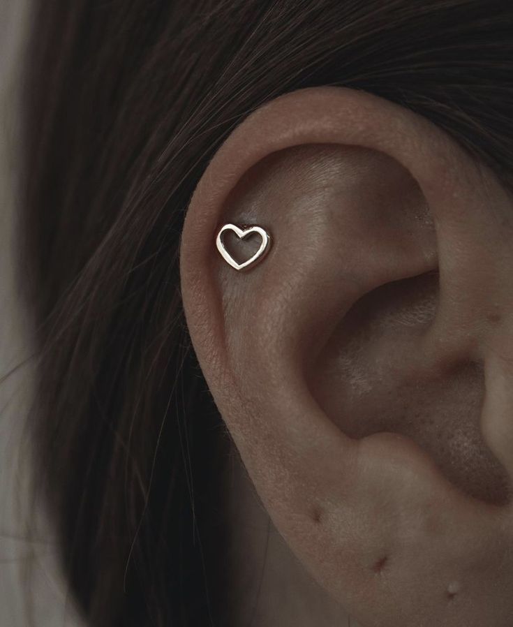 a woman's ear is shown with a heart shaped piercing on the side of her ear