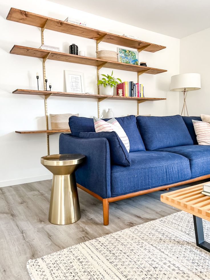 a living room with a blue couch and wooden shelves on the wall, along with a coffee table