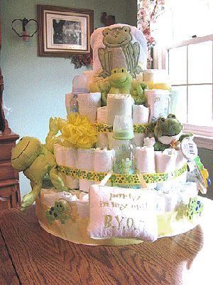 a baby shower cake with teddy bears and diapers on the bottom tier, sitting on a table in front of a window