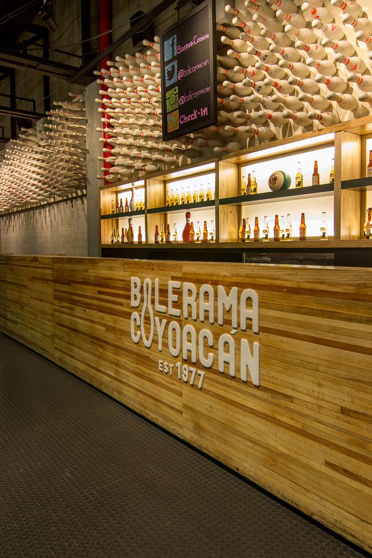 a wooden counter with bottles on it in a room filled with shelves full of bottles