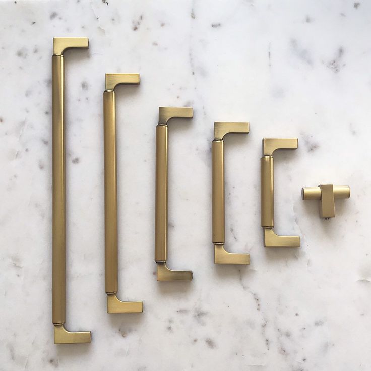 five brass handles on a marble surface