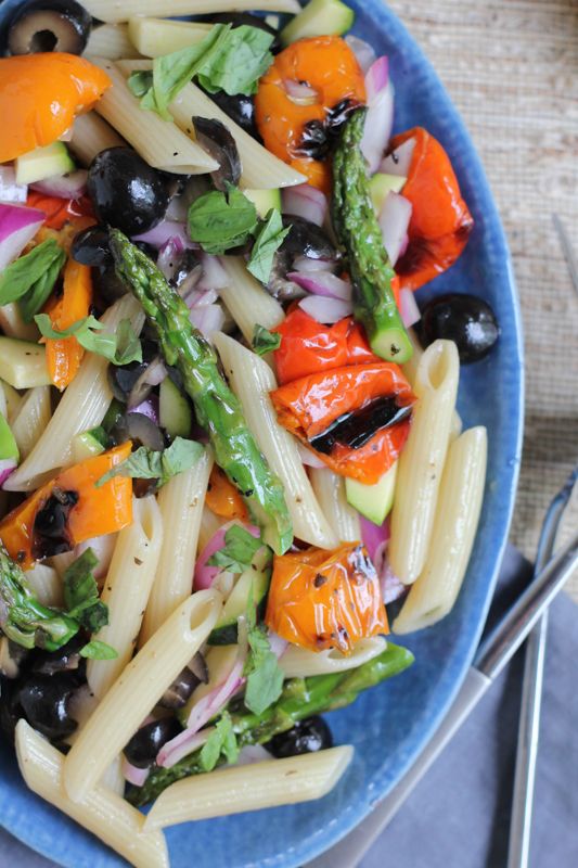 pasta salad with asparagus, carrots and black olives in a blue bowl