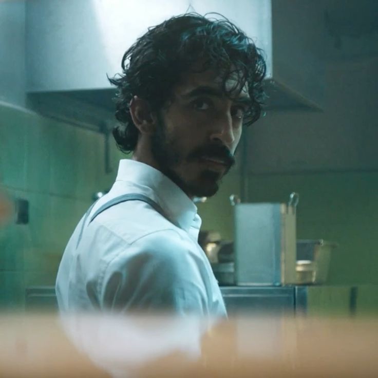 a man in a white shirt and tie standing in a kitchen