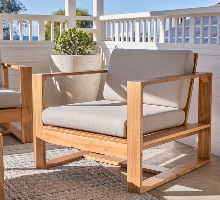 a wooden chair sitting on top of a patio next to a potted plant