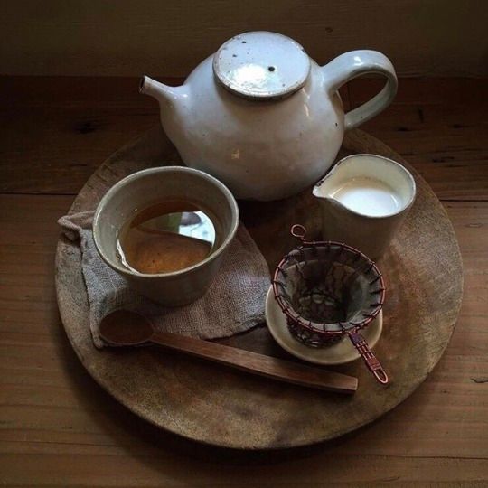 there is a tea pot and two cups on the plate with spoons next to it