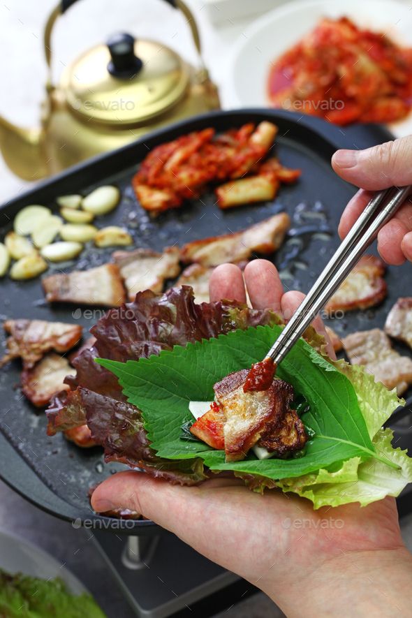 a person holding chopsticks over a plate with meat and vegetables on it - stock photo - images