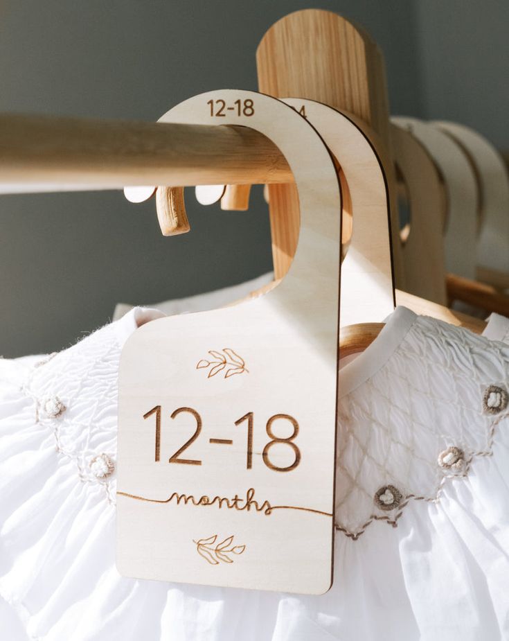 a wooden baby's dress hanger with the date and birth month on it