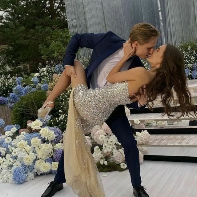 a man and woman are dancing on the dance floor in front of blue and white flowers