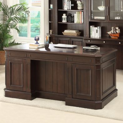 an office desk with bookcases and cabinets in the middle of a living room