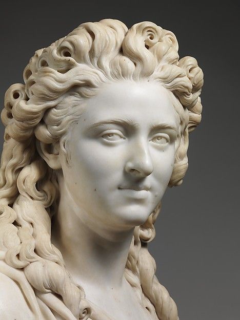 a white marble bust of a woman with curly hair