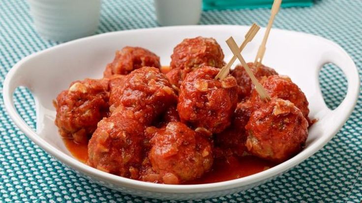 a white bowl filled with meatballs on top of a blue and white table cloth