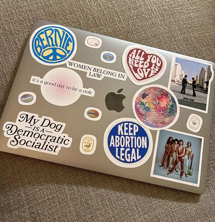 an apple laptop covered in stickers on the back of it's cover,