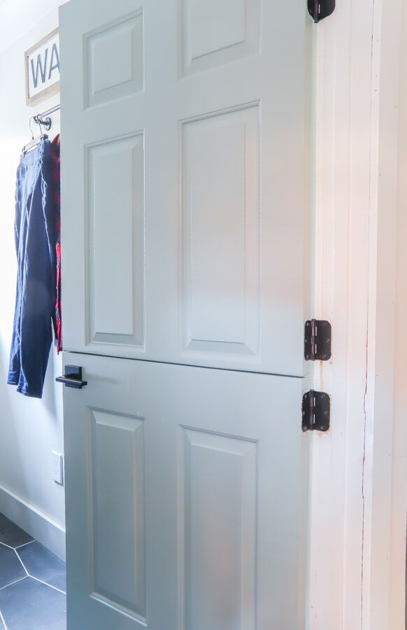 an open white door with clothes hanging on the wall and tiled floor in front of it