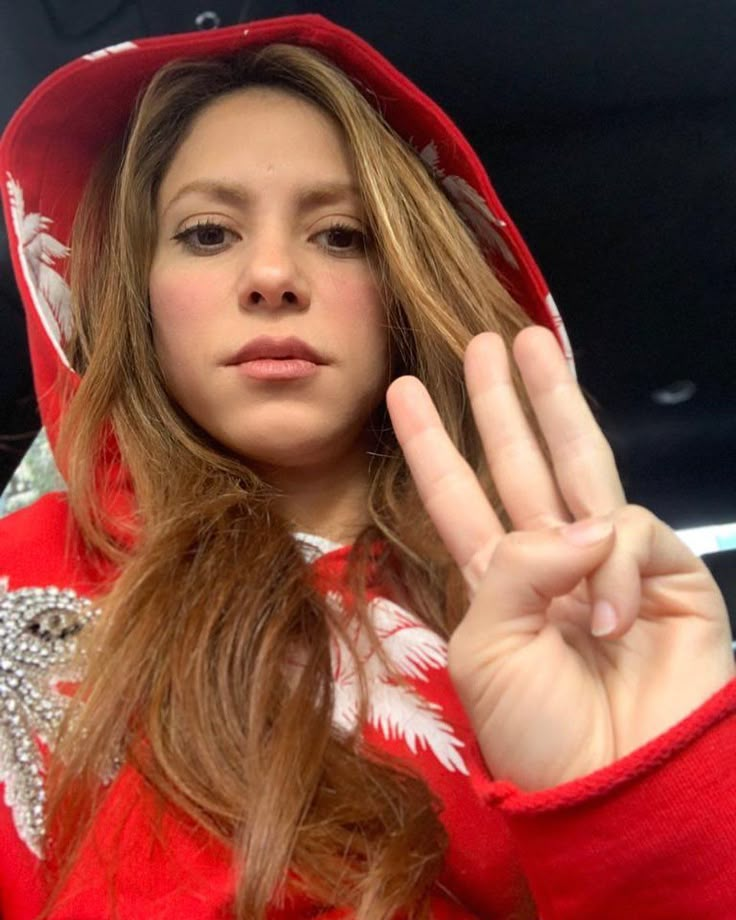 a woman in a red hoodie making the vulcan sign