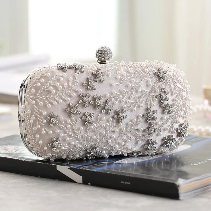 Searching for the perfect accessory to elevate your wedding dress or evening attire? The Crystal Elegance Pearl Beaded Clutch is a stunning choice that exudes romantic sophistication and poetic charm. An elegant statement clutch featuring a delicate beaded design with white pearls and crystals, complemented by silver hardware and a smooth satin back. Its crisp, feminine style makes it a standout piece for any big days and special occasion. Why We Love It... We adore the intricate beaded floral d Bridal Clutch Purse, Embroidered Clutch Bag, Wedding Clutch Purse, Prom Clutch, Purse Luxury, Pearl Clutch, Bridal Handbags, Clutch Bag Wedding, Embroidered Clutch